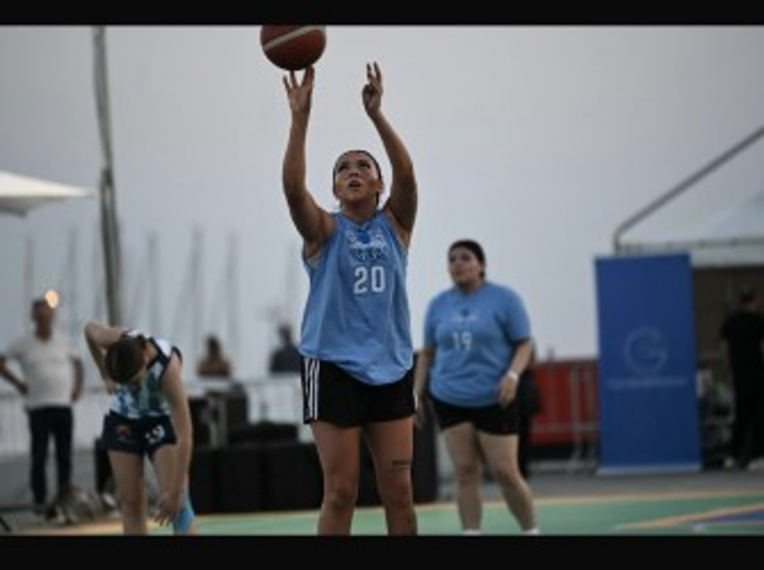 Young player shooting a basketball at an outdoor court during a youth tournament